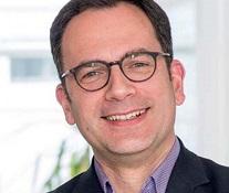 Male with dark hair and glasses, he is smiling
