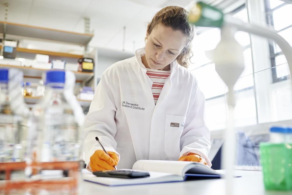 Scientist in lab writing in notebook